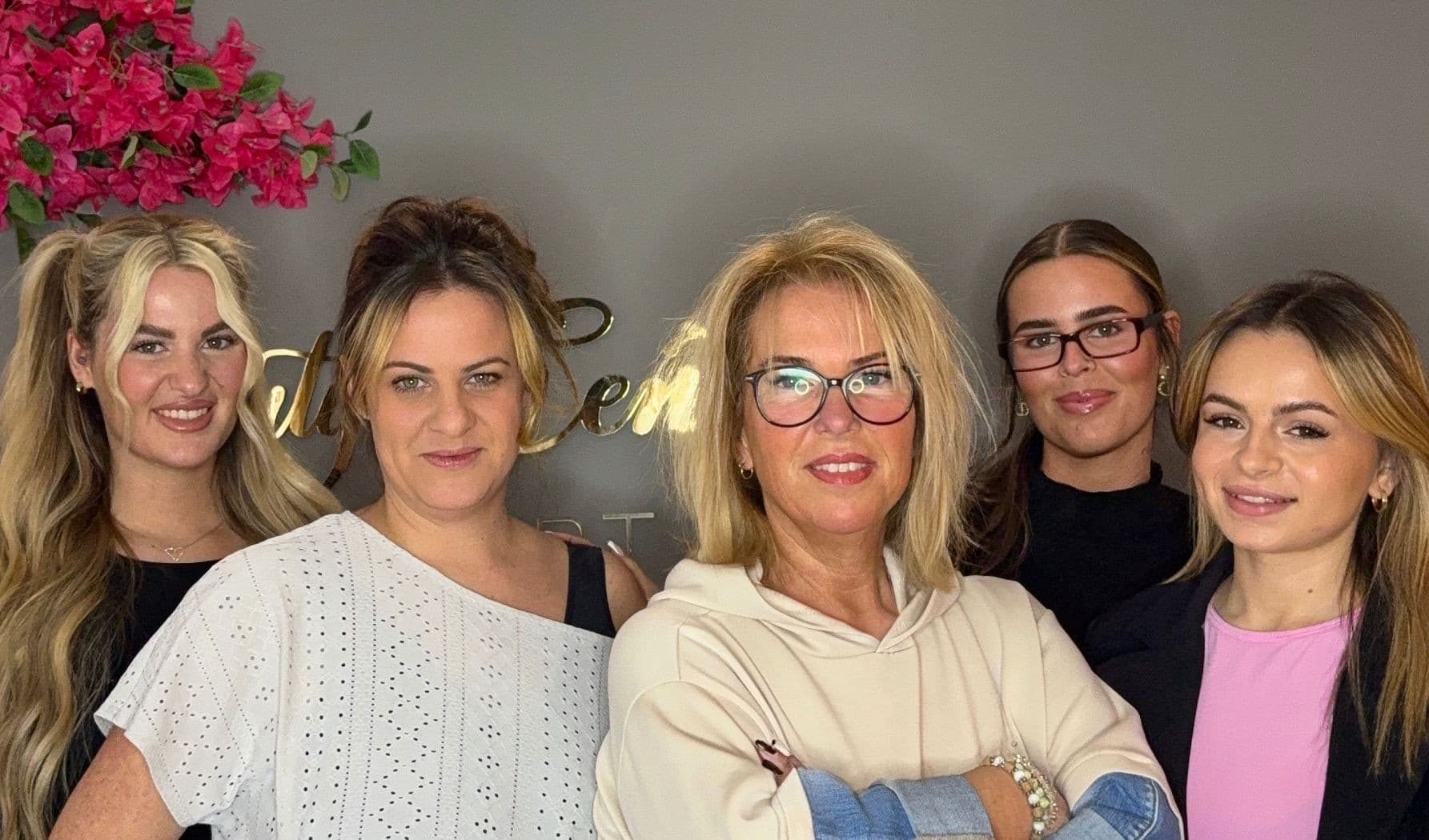 Das Team des Beauty Center by Lambert, fünf Frauen vor der Studiowand mit goldenem Schriftzug